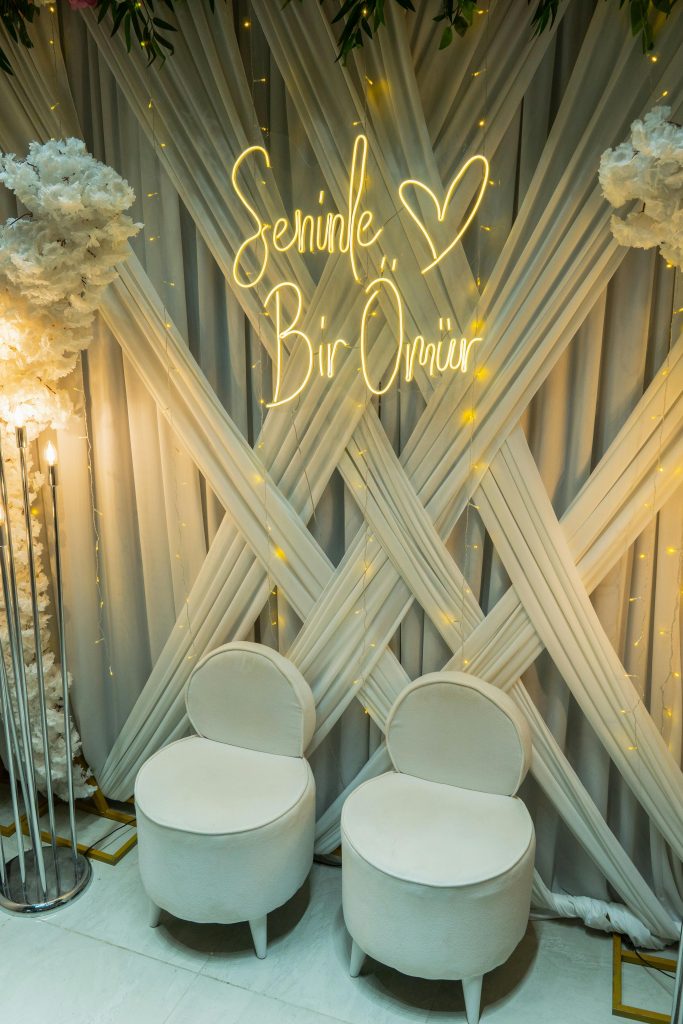 A beautifully decorated wedding backdrop with neon sign and chairs, perfect for photography.
